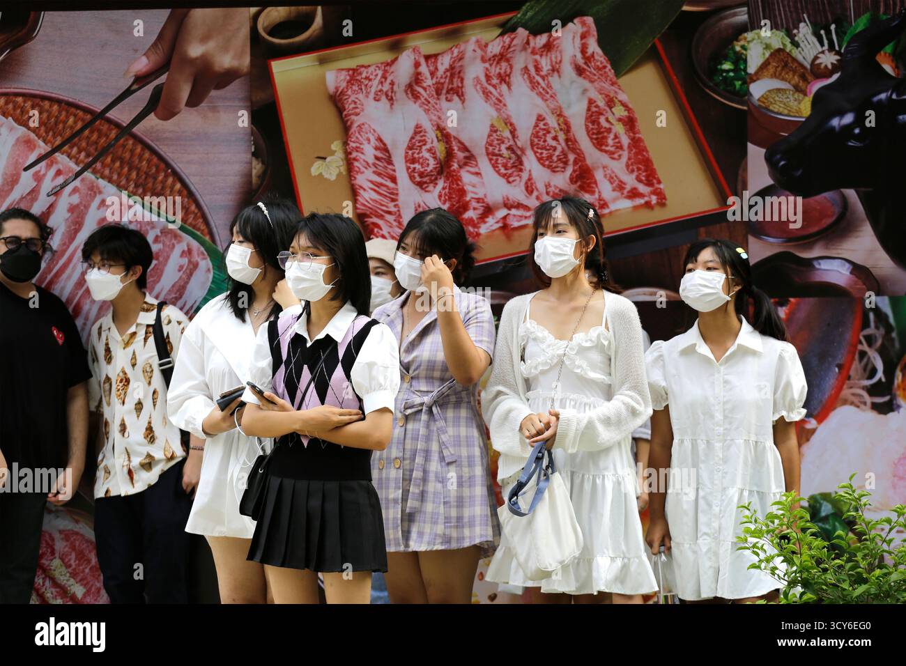 Bangkok, Thaïlande - 31 juillet 2022 : un groupe de filles, portant des masques faciaux en raison de COVID-19, sont vues sur Siam Square, un boulevard de rue piétonne. Banque D'Images