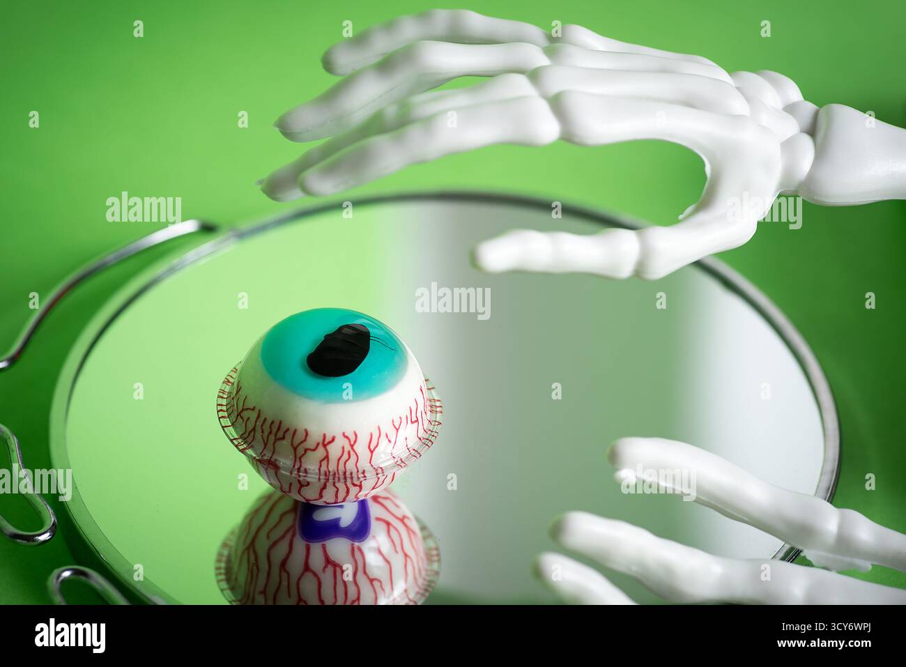 Une scène illustrative mettant en scène la main d'un squelette qui tend délicatement vers un œil réaliste, représentant de manière éclatante des vaisseaux sanguins complexes contre une lumière vive Banque D'Images