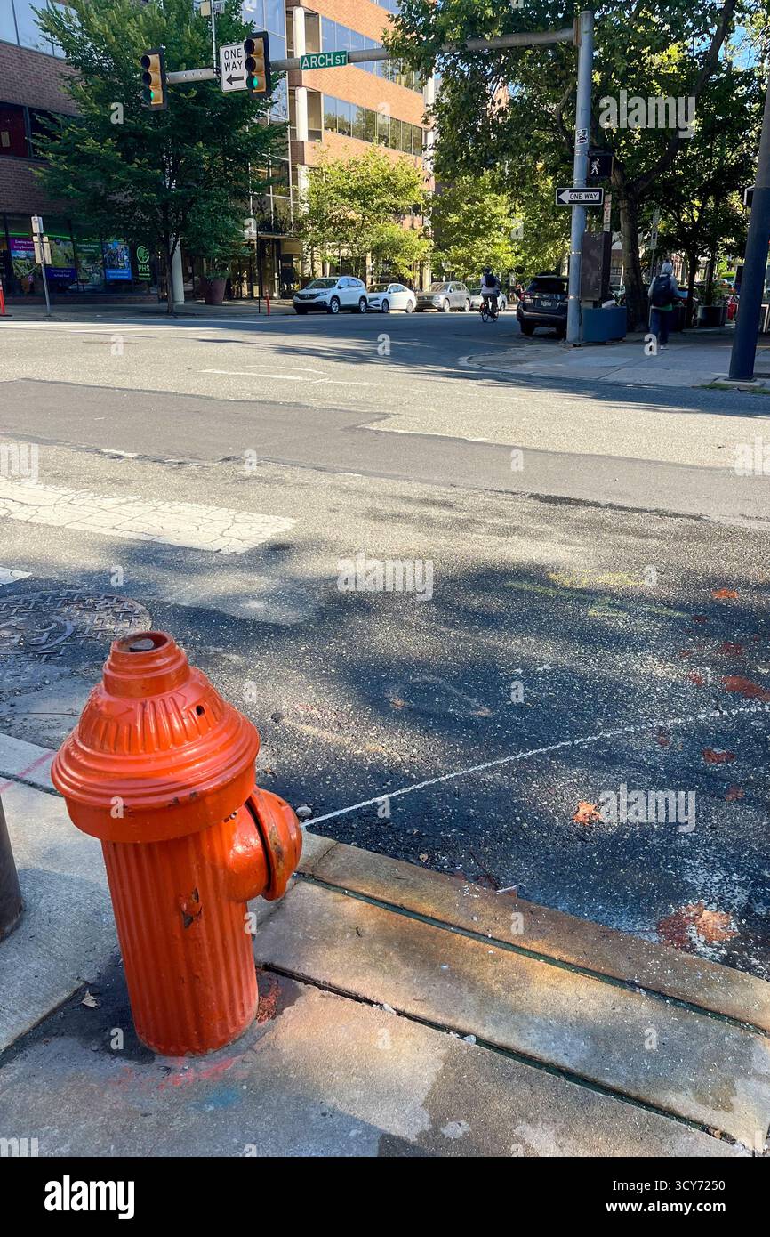 Une bouche d'incendie rouge se trouve sur le trottoir devant un bâtiment. La bouche d'incendie est orange et est située sur le côté de la route Banque D'Images Une bouche d'incendie rouge se trouve sur le trottoir devant un bâtiment. La bouche d'incendie est orange et est située sur le côté de la route Banque D'Images
