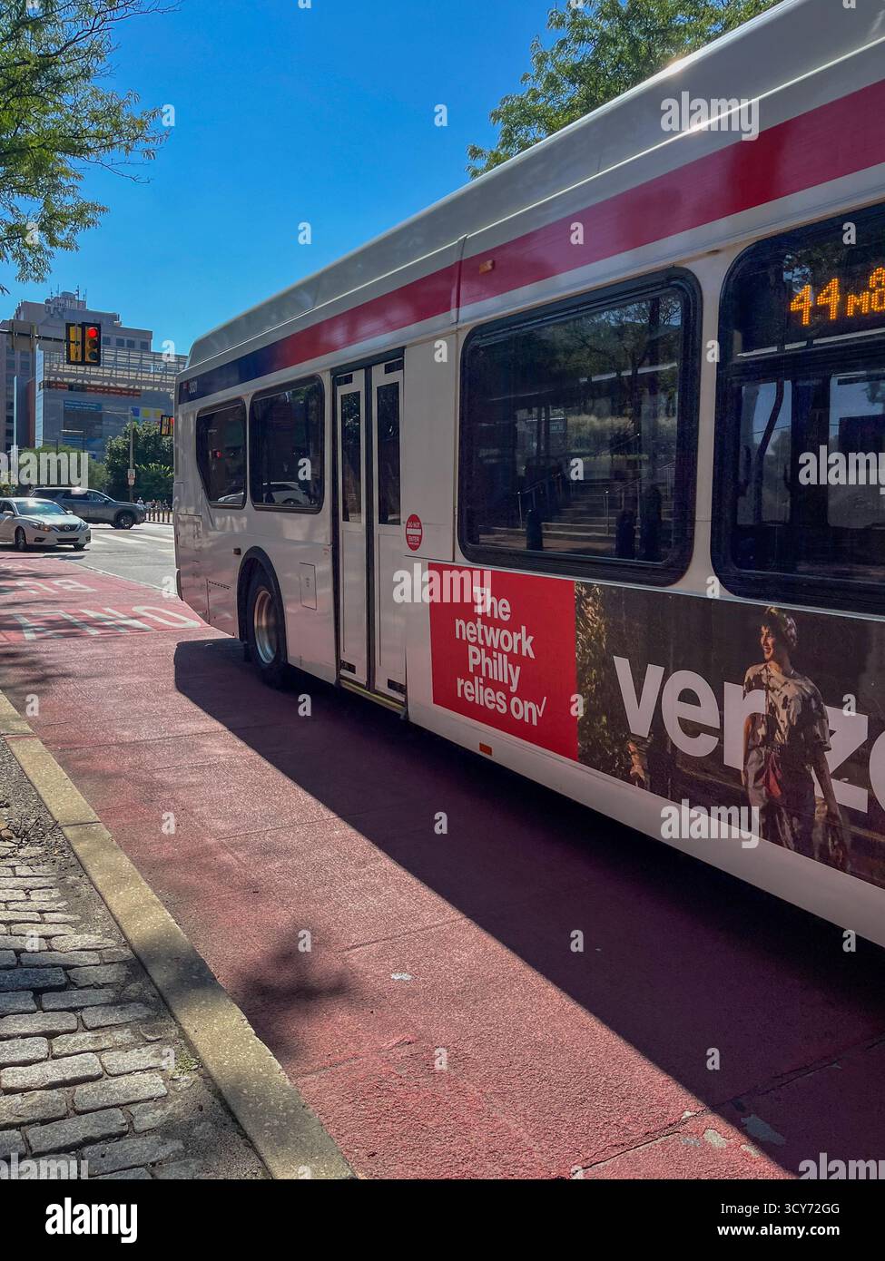Un bus blanc et rouge avec Verizon sur le côté. Le bus est garé sur le bord de la route Banque D'Images Un bus blanc et rouge avec Verizon sur le côté. Le bus est garé sur le bord de la route Banque D'Images