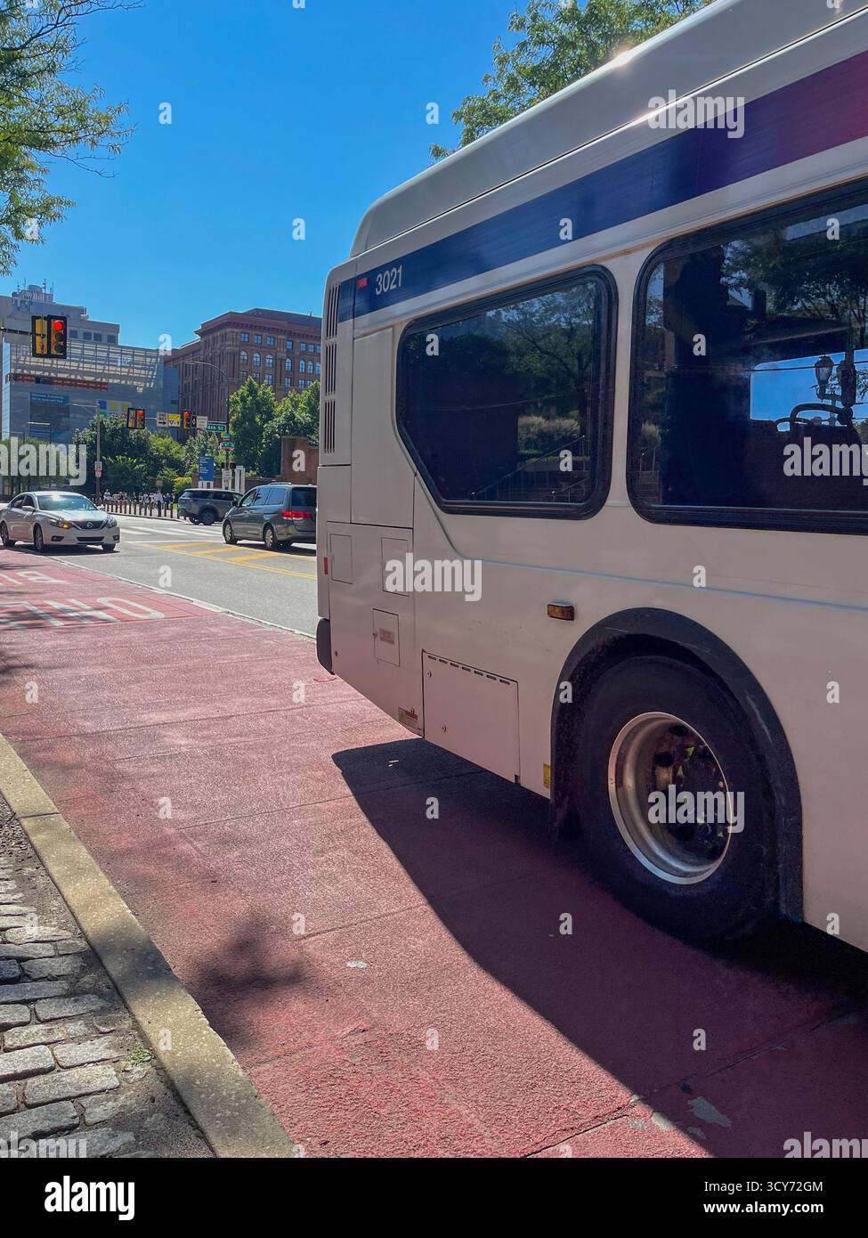 Un bus blanc est garé sur le bord de la route. Le bus est sur une ligne rouge, ce qui indique qu'il n'est pas autorisé à entrer dans la rue Banque D'Images Un bus blanc est garé sur le bord de la route. Le bus est sur une ligne rouge, ce qui indique qu'il n'est pas autorisé à entrer dans la rue Banque D'Images