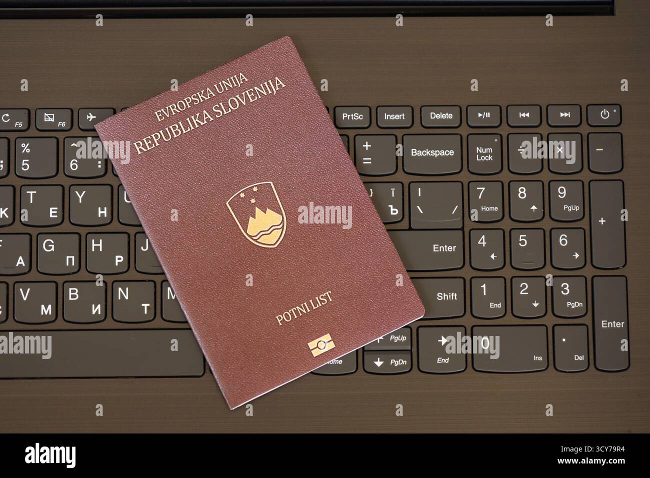 Passeport slovène se trouve sur fond noir de boutons de clavier d'ordinateur portable gros plan. Technologies et contrôle en Europe concept Banque D'Images