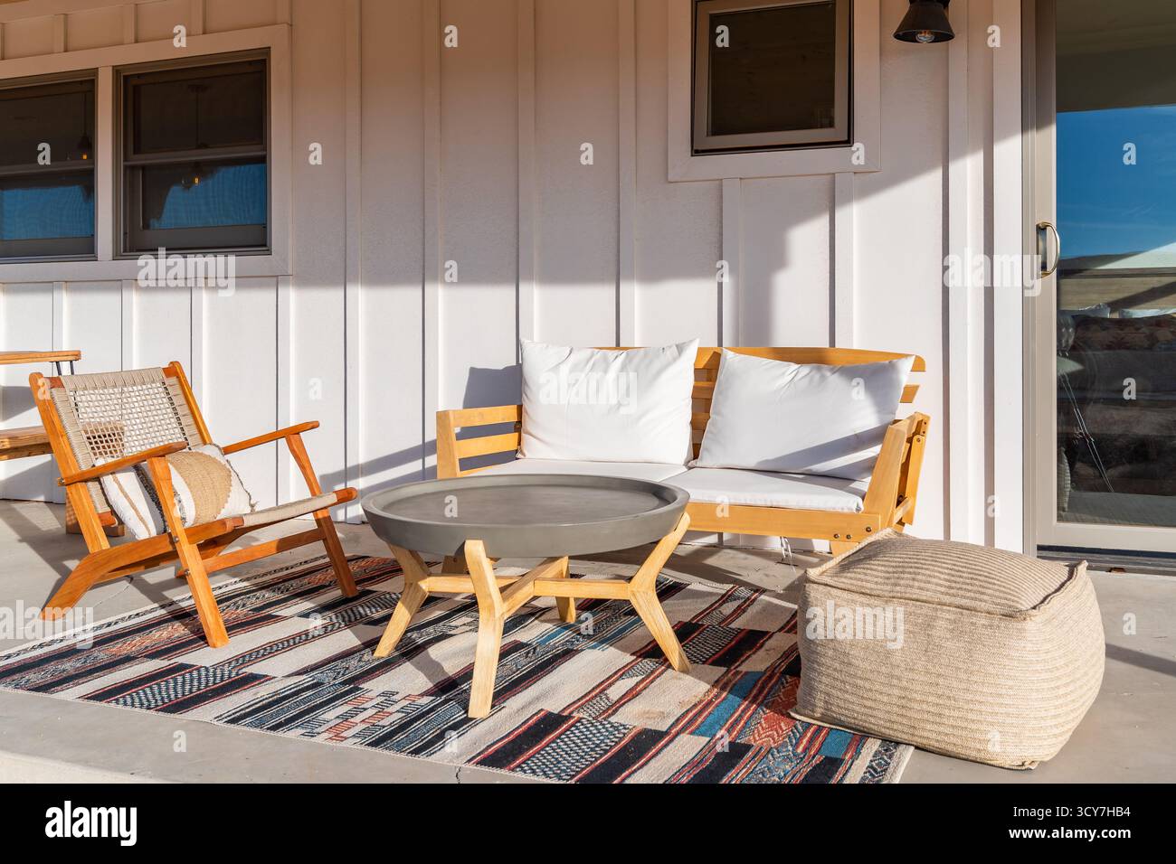 Patio ensoleillé meubles modernes en bois sièges, table en béton, tapis coloré. Joshua Tree, Californie. Banque D'Images