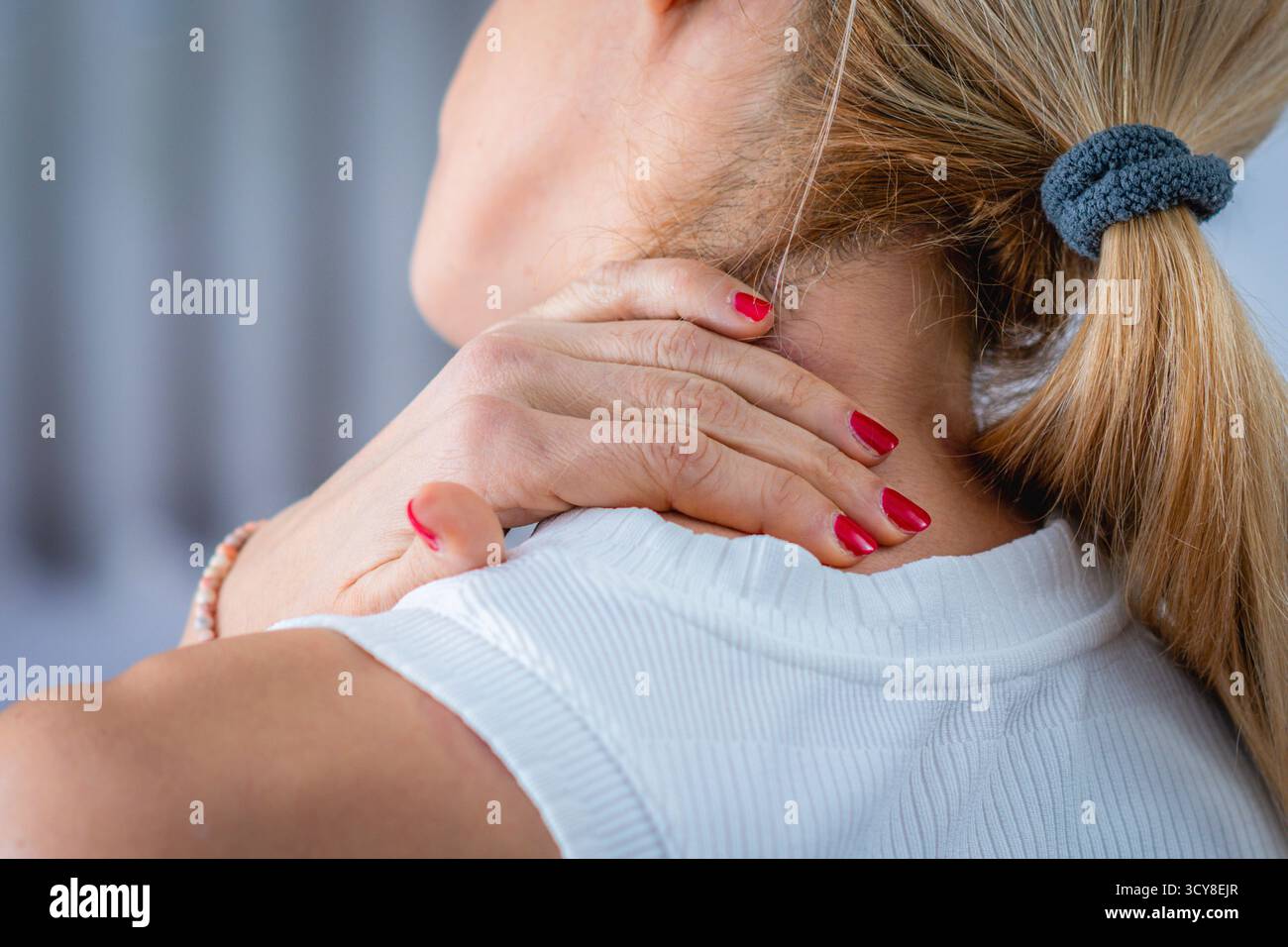 La douleur au cou est ressentie par une femme qui s'auto-masse le cou. Banque D'Images