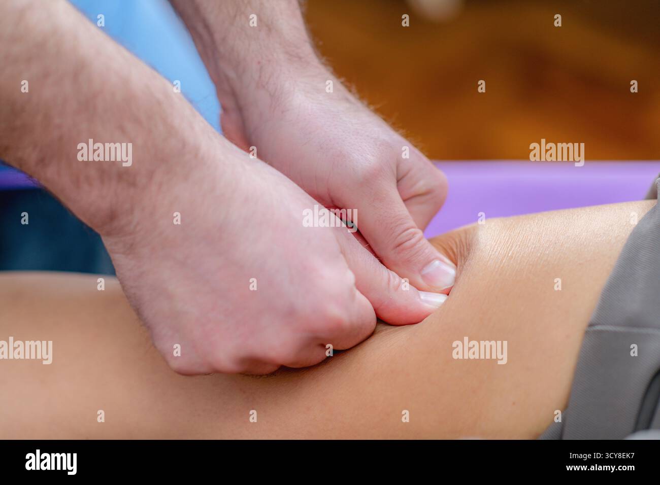 Femme recevant un massage du genou pendant une séance de physiothérapie pour soulager la tension musculaire, améliorer la circulation et réduire les douleurs articulaires. Banque D'Images