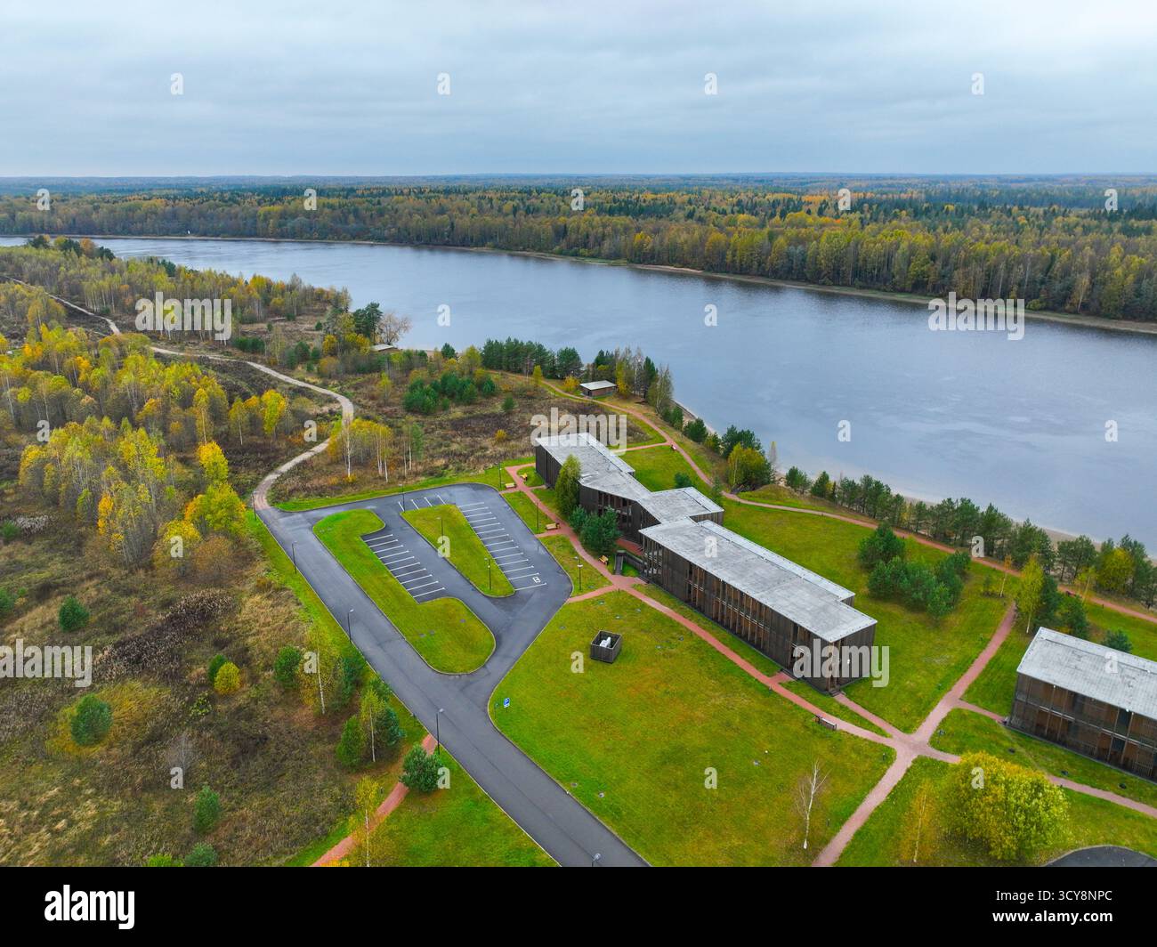 Morozova, oblast de Leningrad, Russie - 13 mai 2024 : vue aérienne d'un complexe hôtelier moderne étendu et d'un parking le long d'une large rivière, entouré par Banque D'Images