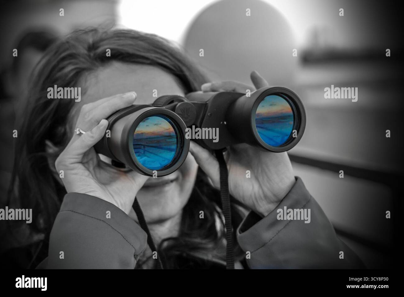 Portrait noir et blanc avec paysage éclatant reflété dans les jumelles. Le contraste artistique suggère vision et exploration. Banque D'Images