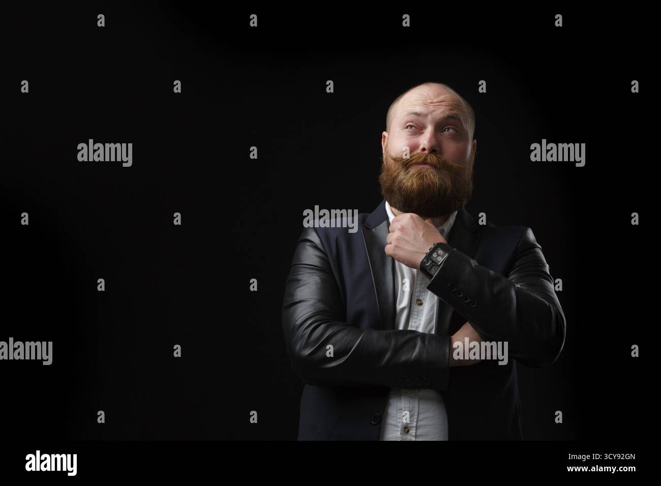 Homme pensif avec barbe de gingembre et moustache sur fond noir Banque D'Images