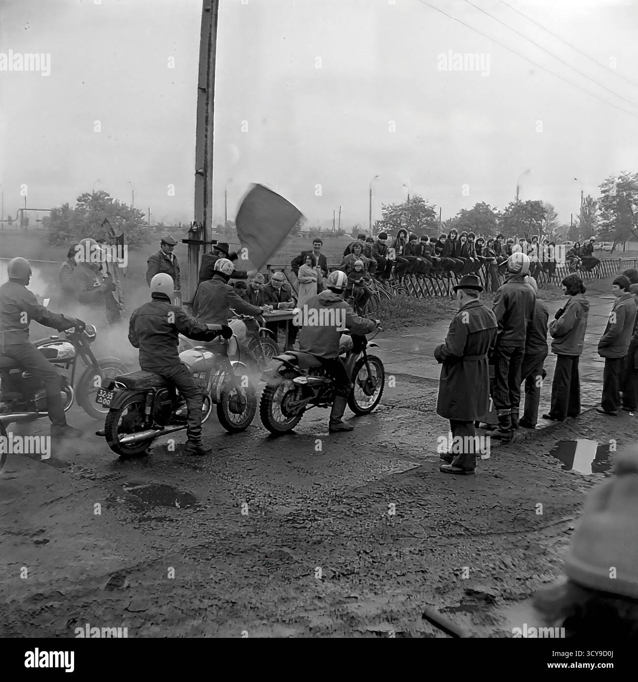 Une photo d'archives dynamique des années 1970 capture l'atmosphère gracieuse d'une course de motocross à Sloviansk, en RSS d'Ukraine. Les coureurs vêtus de casques vintage et d'équipements de protection chevauchent leurs puissantes motos de l'ère soviétique (probablement des modèles CZ ou Izh) sur une piste boueuse de terre, prêts pour la compétition. Les spectateurs se rassemblent à proximité, ajoutant à l'excitation de l'événement de sport automobile local. Cette image dépeint de manière éclatante la passion pour le sport et les rassemblements communautaires dans un Donbass pacifique avant la guerre Banque D'Images
