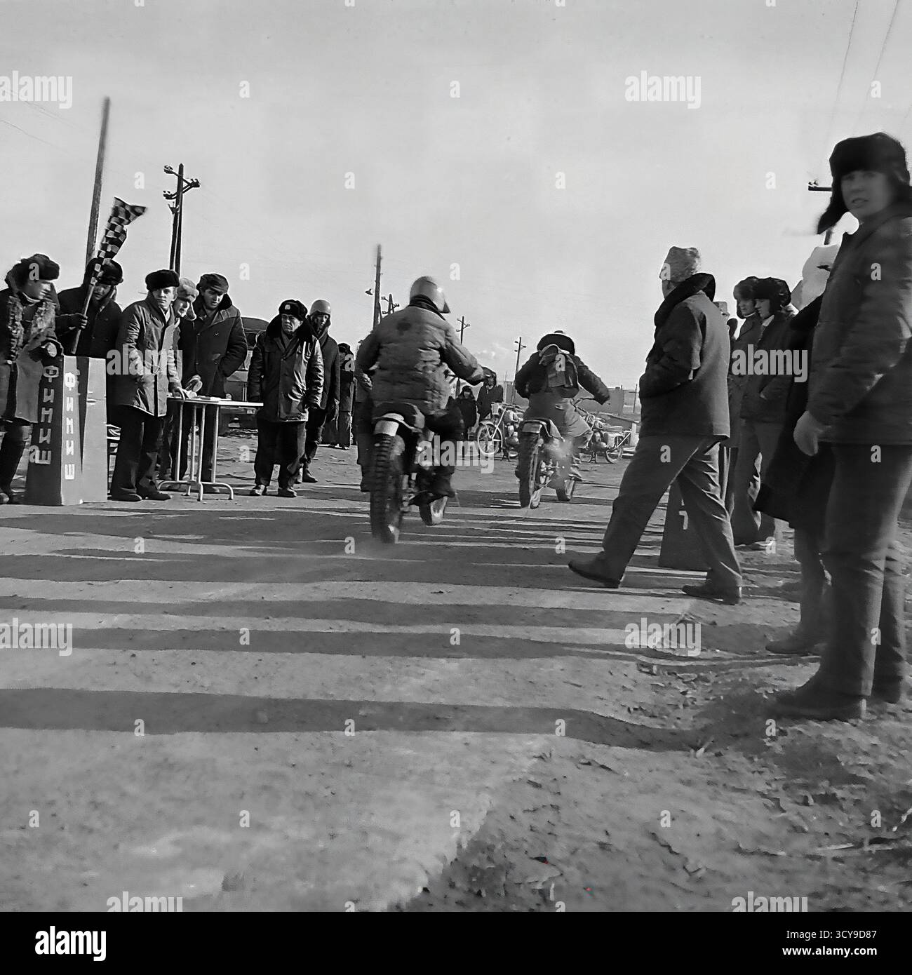 Une photo d'archives dynamique des années 1970 capture l'atmosphère gracieuse d'une course de motocross à Sloviansk, en RSS d'Ukraine. Les coureurs vêtus de casques vintage et d'équipements de protection chevauchent leurs puissantes motos de l'ère soviétique (probablement des modèles CZ ou Izh) sur une piste boueuse de terre, prêts pour la compétition. Les spectateurs se rassemblent à proximité, ajoutant à l'excitation de l'événement de sport automobile local. Cette image dépeint de manière éclatante la passion pour le sport et les rassemblements communautaires dans un Donbass pacifique avant la guerre Banque D'Images