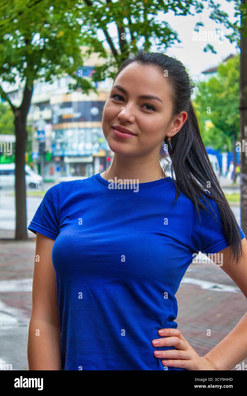 Escapade urbaine : individu souriant dans un tee-shirt bleu au milieu de la nature en toile de fond Banque D'Images