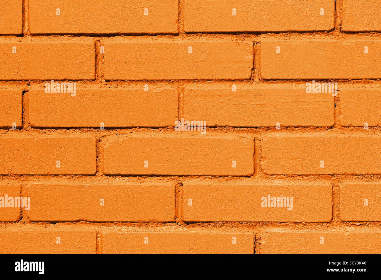 Gros plan de la texture du mur de briques orange. Fond de briques peintes brillantes avec motif géométrique et détail de surface rugueux. Banque D'Images