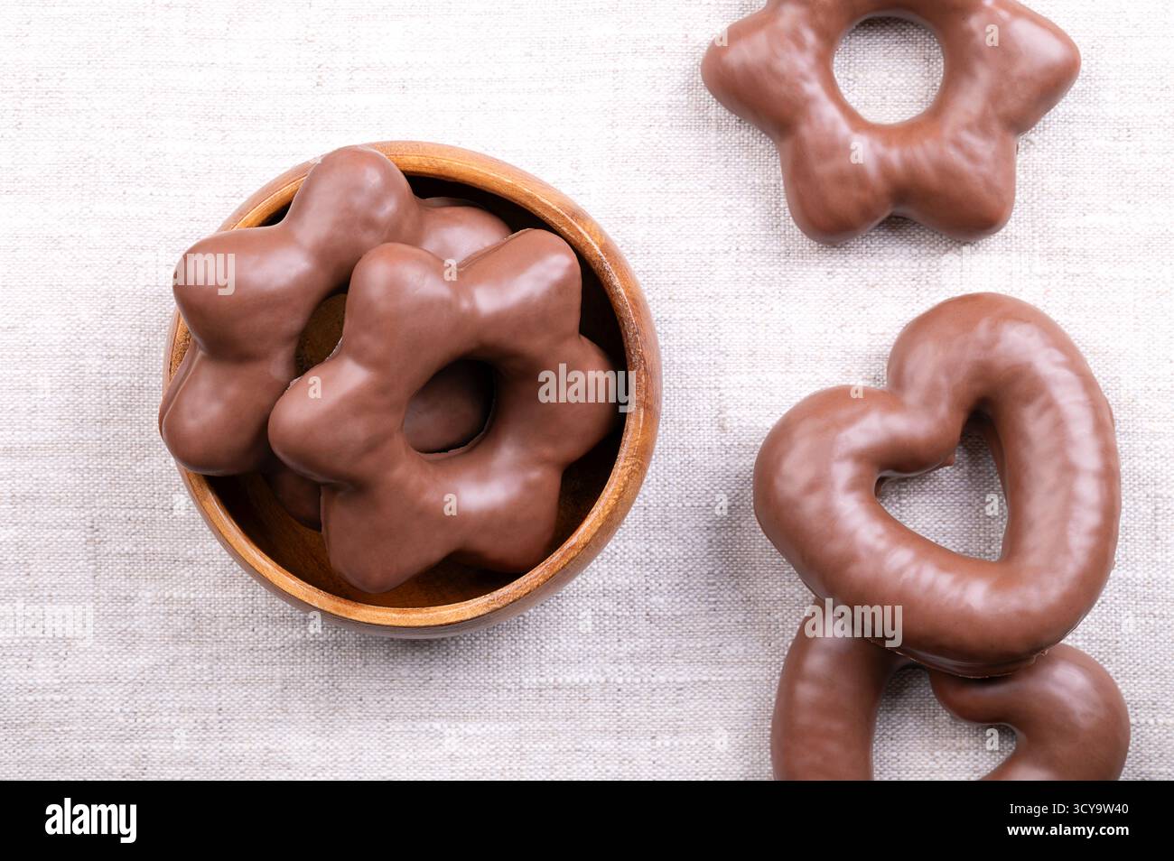 Pain d'épices trempé dans du chocolat, dans un bol blanc, sur du lin. Lebkuchen allemand traditionnel en forme de coeur et d'étoile, entièrement enrobé de chocolat au lait. Banque D'Images