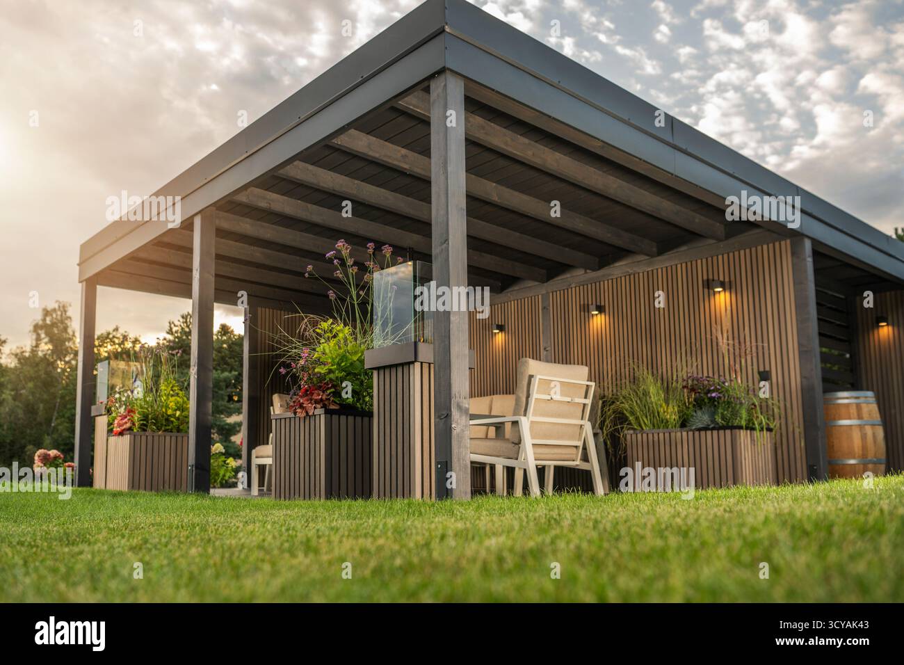 Cet espace extérieur dispose de sièges confortables, de plantes et d'un éclairage chaleureux, parfait pour se détendre dans la lueur du soir. Banque D'Images