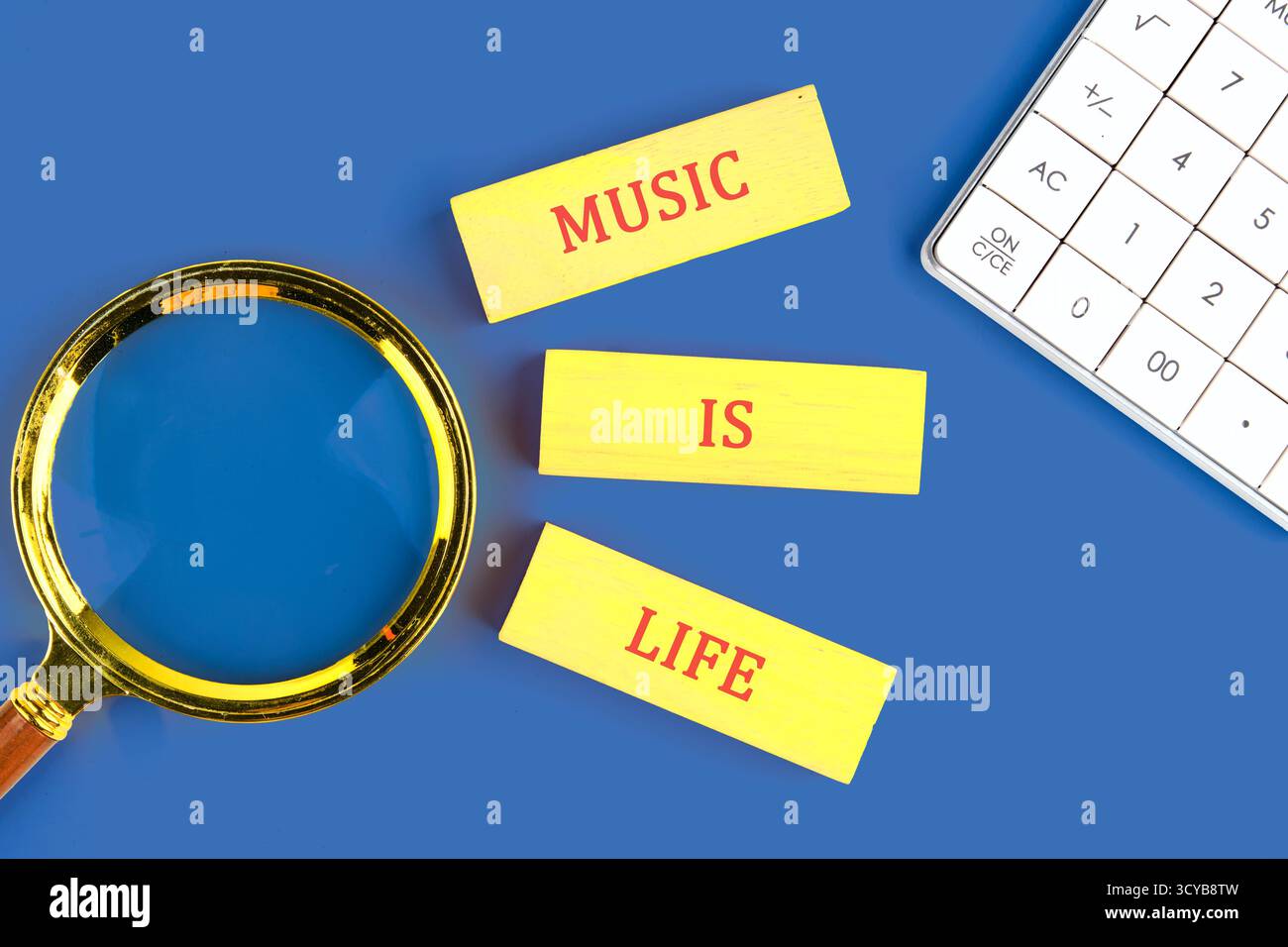Les cartons jaunes vifs indiquent que la musique est la vie aux côtés d'une loupe et d'une calculatrice sur fond bleu, soulignant le rôle de la musique dans la compréhension de notre Banque D'Images