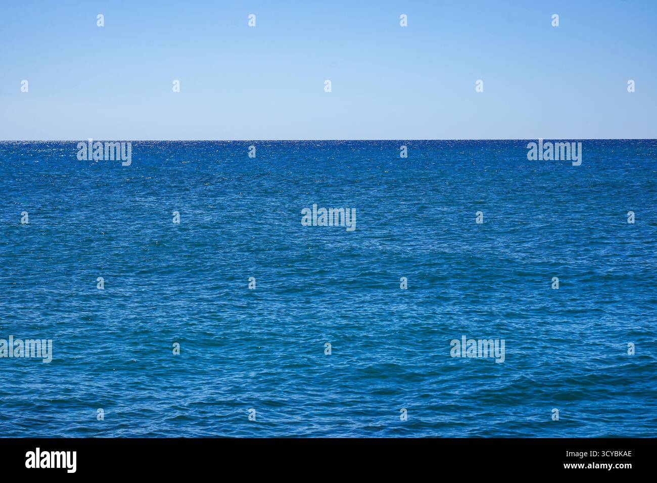Vaste océan Azur sous un ciel clair, mettant en valeur des eaux tranquilles et un horizon sans fin tandis que la lumière du jour illumine la vue sereine sur la côte Banque D'Images