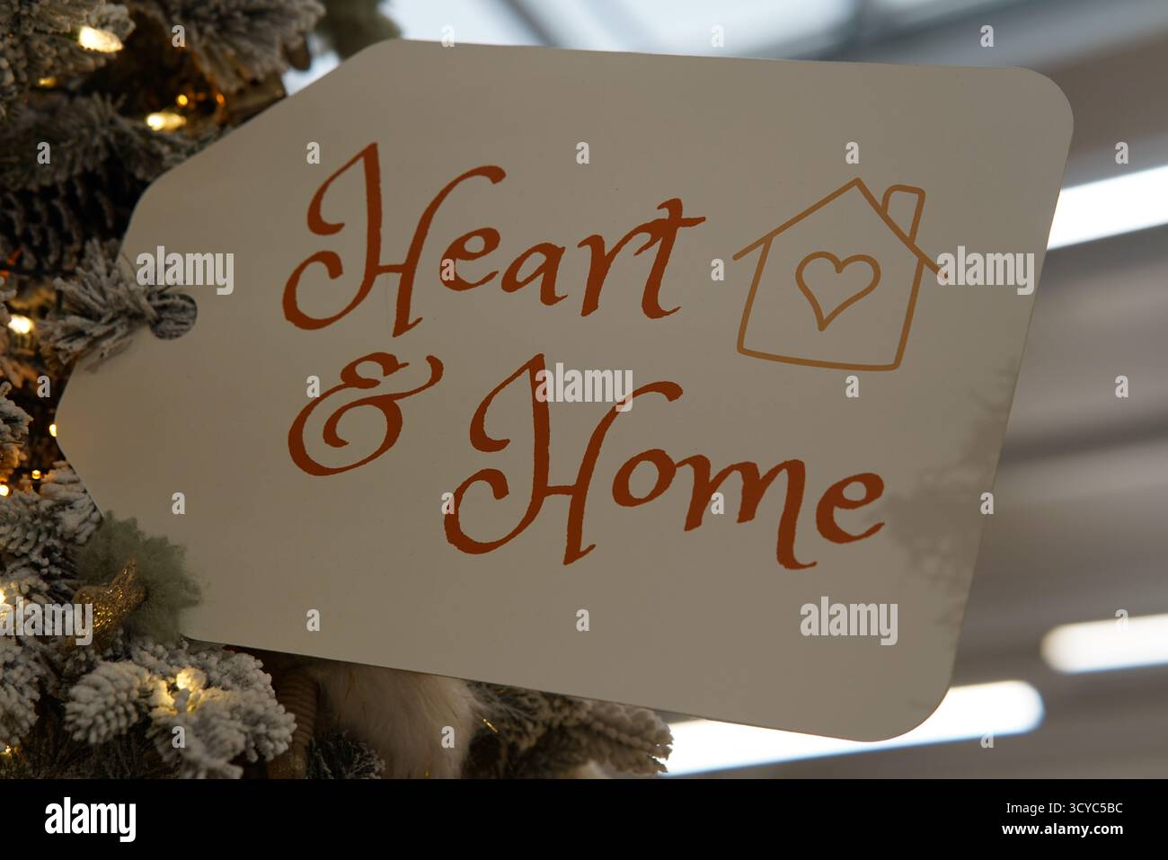 Panneau décoratif « Heart & Home » affiché sur un arbre de Noël au Haskins Garden Centre, symbolisant la chaleur festive et l’esprit de famille. Banque D'Images