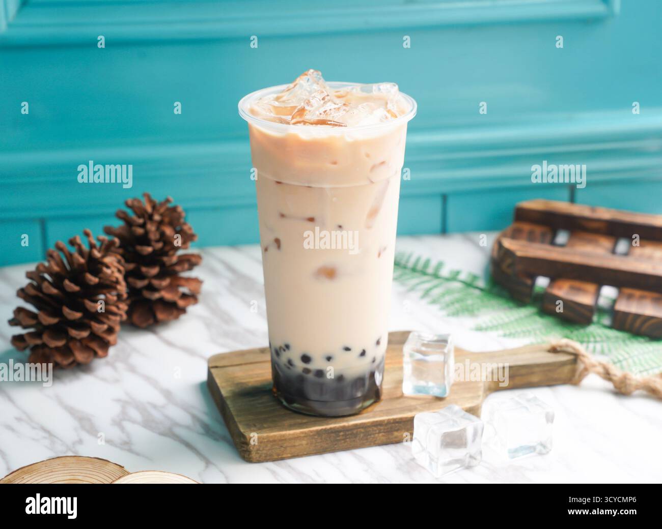 Thé au lait de perle glacé avec glaçon dans un grand verre servi sur une planche en bois vue latérale de la boisson froide de taiwan Banque D'Images
