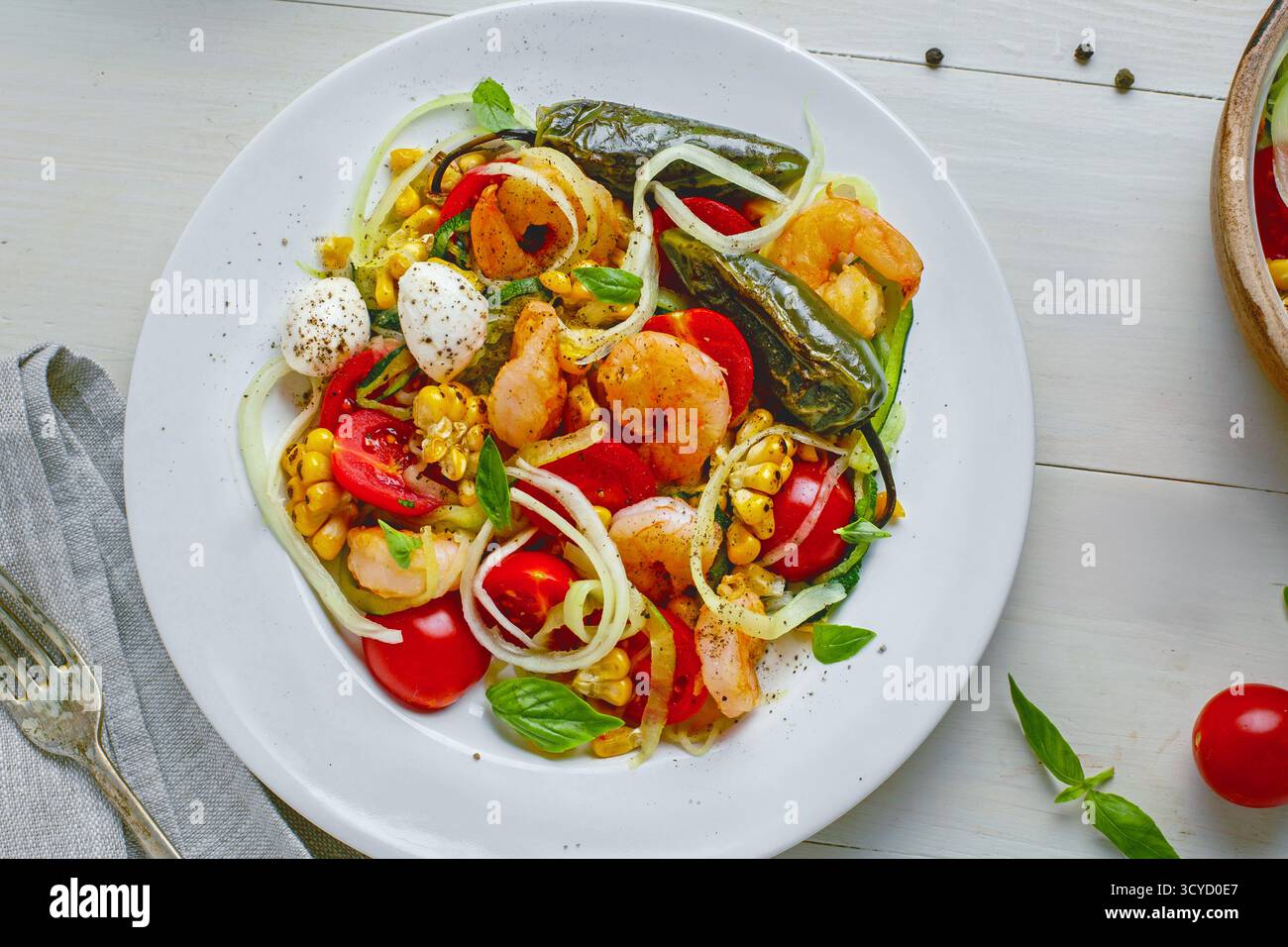 Pâtes aux courgettes avec crevettes, mini mozzarella, maïs et légumes grillés dans une assiette Banque D'Images