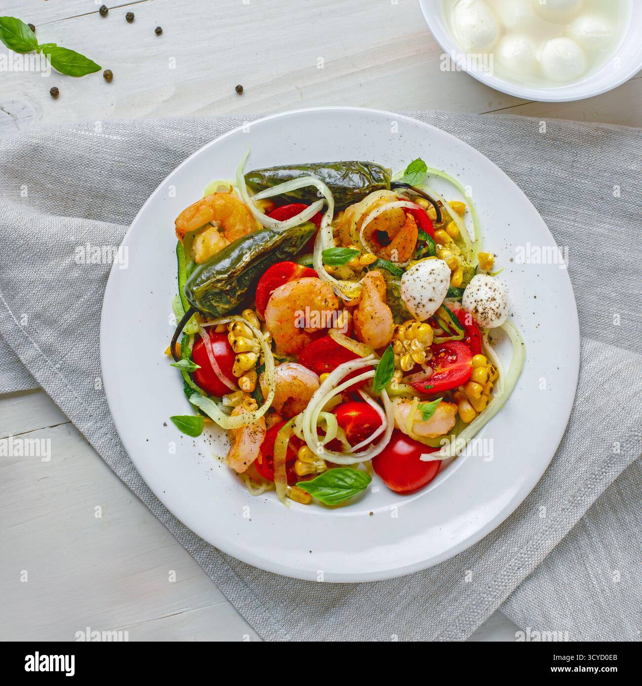 Pâtes aux courgettes avec crevettes, mini mozzarella, maïs et légumes grillés dans une assiette Banque D'Images