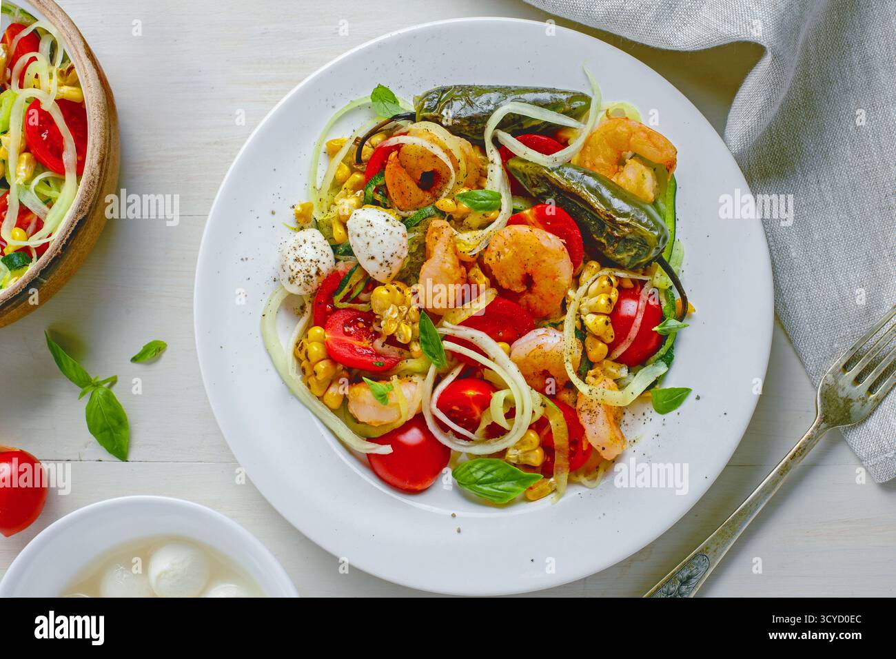 Bol de pâtes aux courgettes de fruits de mer sain avec crevettes, poivre grillé et légumes frais Banque D'Images