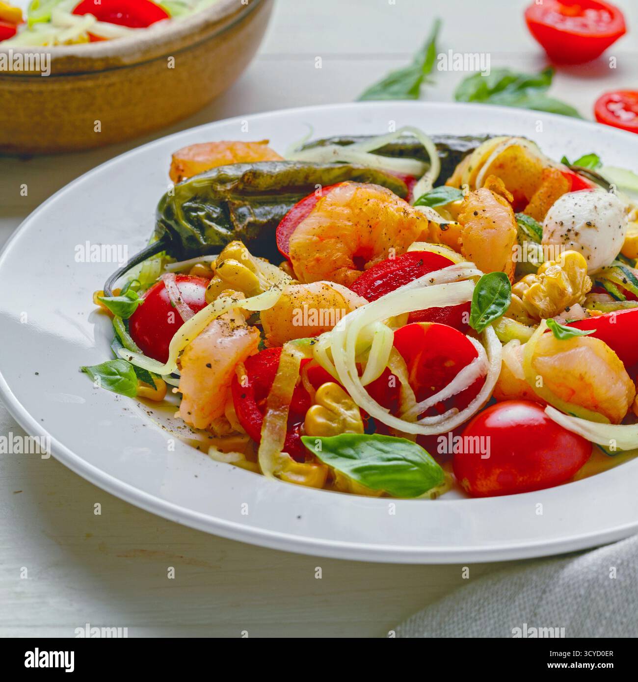 Pâtes aux courgettes avec crevettes, mini mozzarella, maïs et légumes grillés dans une assiette Banque D'Images