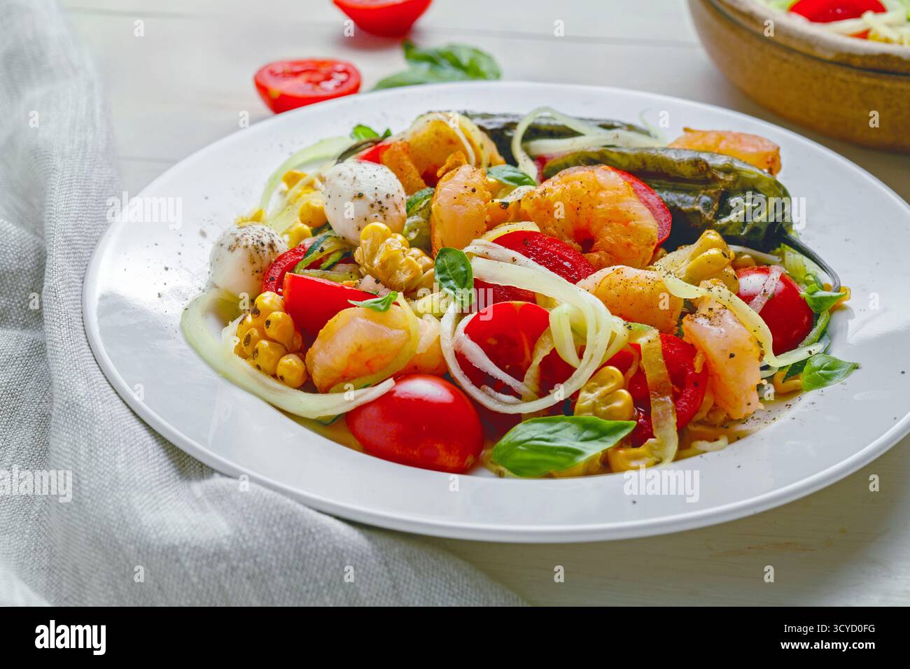 Pâtes aux courgettes avec crevettes, mini mozzarella, maïs et légumes grillés dans une assiette Banque D'Images