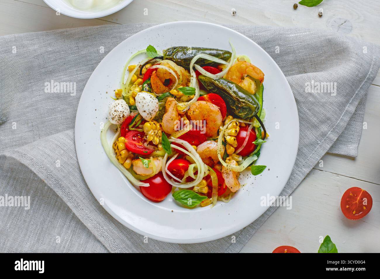 Bol de pâtes aux courgettes de fruits de mer sain avec crevettes, poivre grillé et légumes frais Banque D'Images