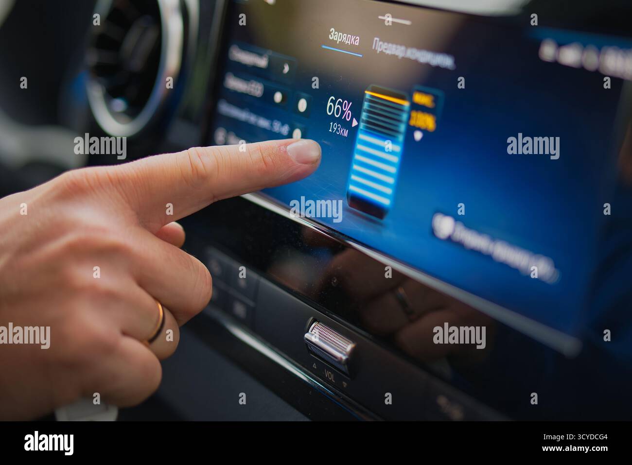 Affichage de charge de voiture électrique avec écran tactile à main montrant le niveau de la batterie et l'autonomie à l'intérieur de l'habitacle moderne du véhicule Banque D'Images