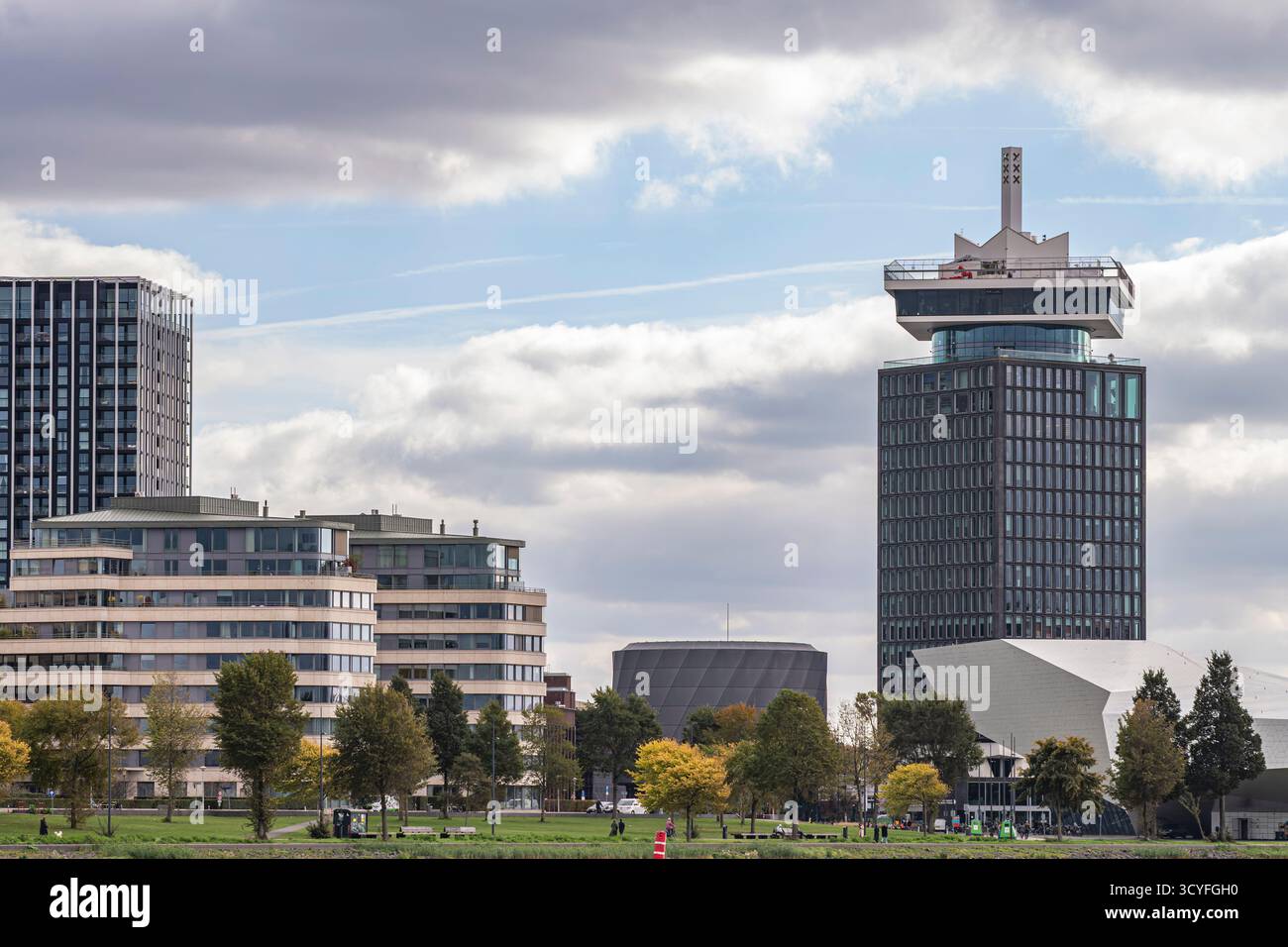 Maisons modernes sur les rives de la rivière Amstel à Amsterdam — vue latérale avec arbres d'automne et ciel nuageux Banque D'Images