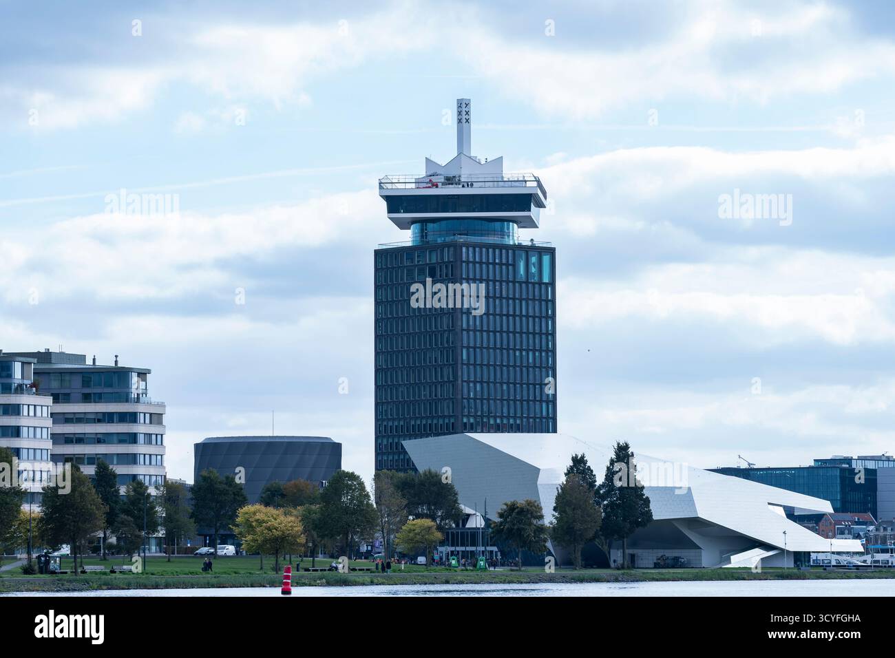 Maisons modernes sur les rives de la rivière Amstel à Amsterdam — vue latérale avec arbres d'automne et ciel nuageux Banque D'Images