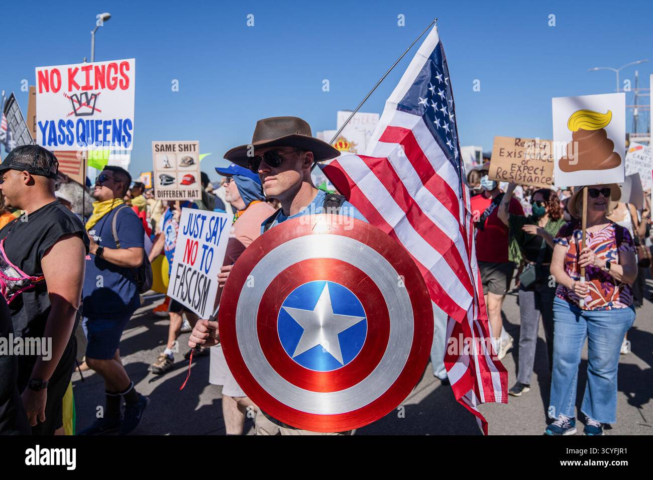 Un manifestant portant un drapeau américain et un bouclier de Captain America marche avec d'autres tenant des pancartes disant « pas de rois » et « dites simplement non au fascisme » pendant la manifestation les manifestants se sont rassemblés dans le centre de San Diego, en Californie, pour prendre part aux manifestations nationales « pas de rois ». Marchant du Civic Center Plaza au Waterfront Park, les participants ont exprimé leur opposition à l'autoritarisme du gouvernement et aux récentes politiques fédérales sous le président Donald Trump. La manifestation, l'une des centaines de manifestations organisées à travers les États-Unis, comportait des bannières, des chants et des spectacles appelant à la démocratie, à l'égalité et à la FRE Banque D'Images