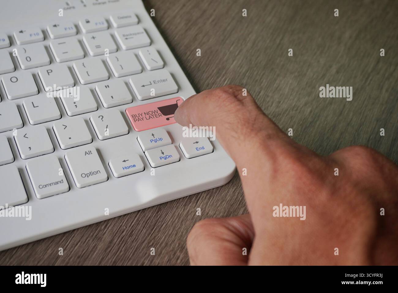 Un doigt appuie sur une touche du clavier intitulée « ACHETER MAINTENANT, PAYER PLUS TARD » avec une icône de panier. Options de paiement échelonné dans le commerce électronique et les achats en ligne Banque D'Images