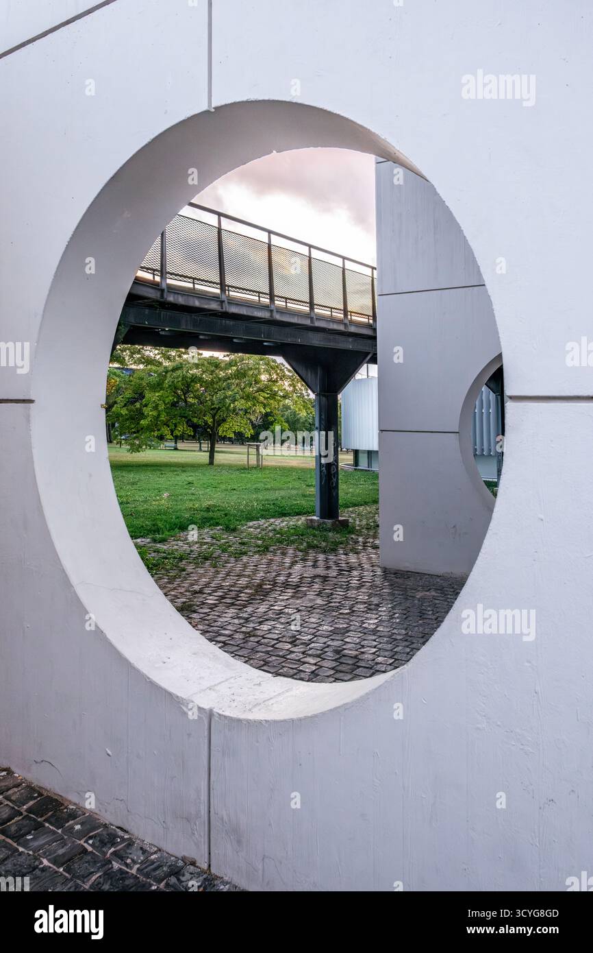 Vue à travers une circulaire architecturale ouvrant sur un pont piétonnier, Green Park et Modern Building dans un cadre urbain Banque D'Images
