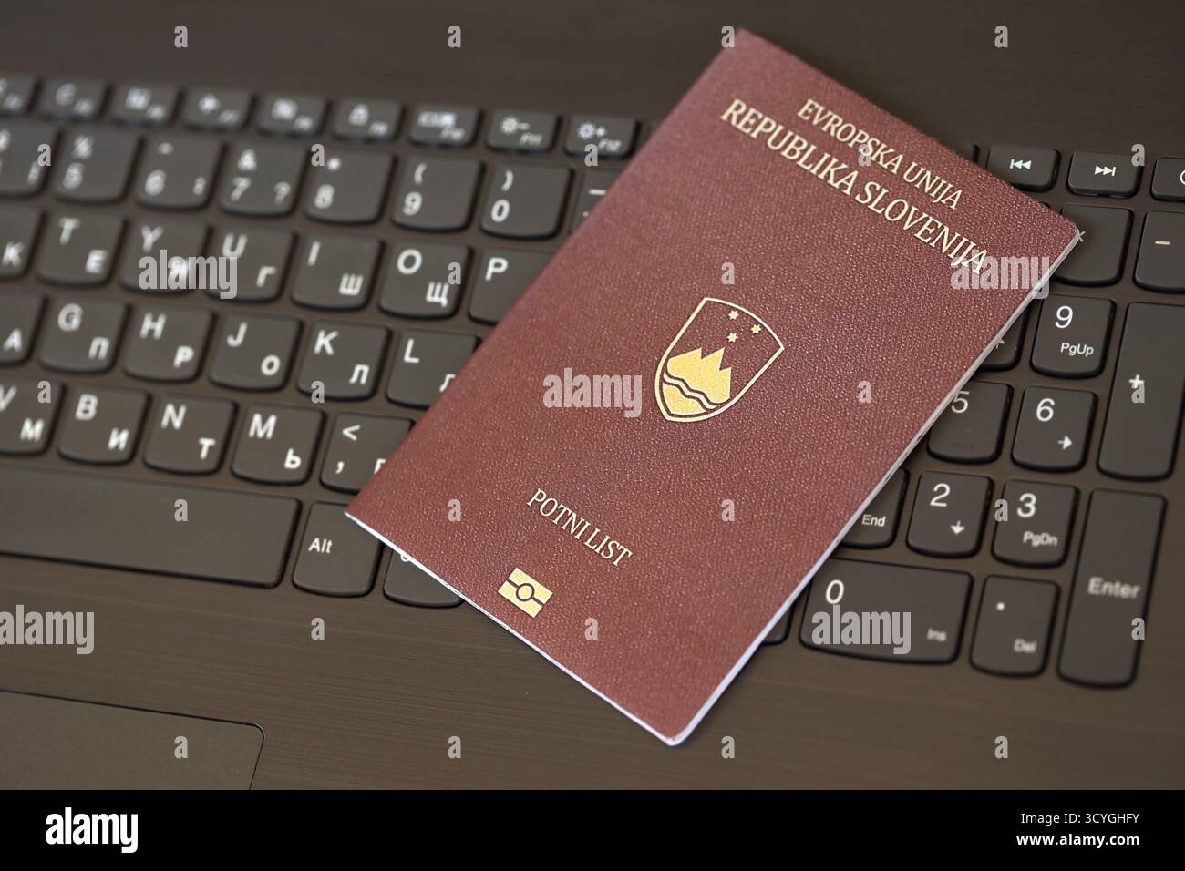 Passeport slovène se trouve sur fond noir de boutons de clavier d'ordinateur portable gros plan. Technologies et contrôle en Europe concept Banque D'Images