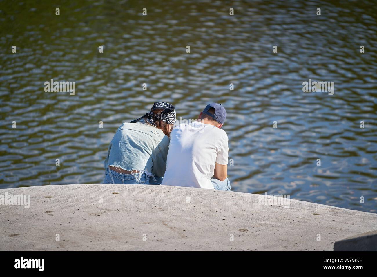 Un couple est assis sur la rive d'un lac et parle Banque D'Images
