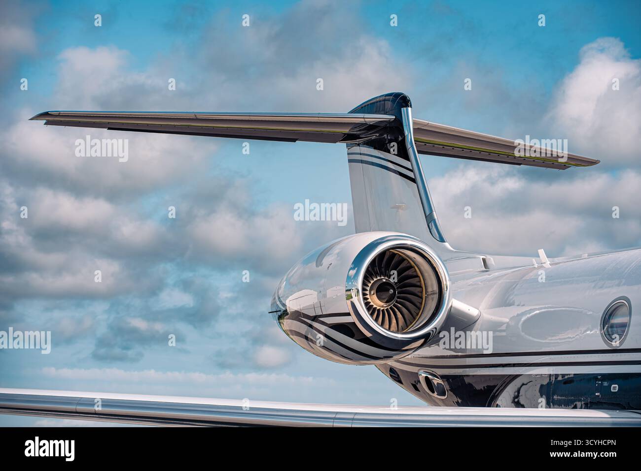 Gros plan d'un turboréacteur à queue d'avion et turboréacteur d'affaires moderne montrant une conception aérodynamique et des pales de soufflante à haut débit sous un ciel partiellement nuageux. Banque D'Images