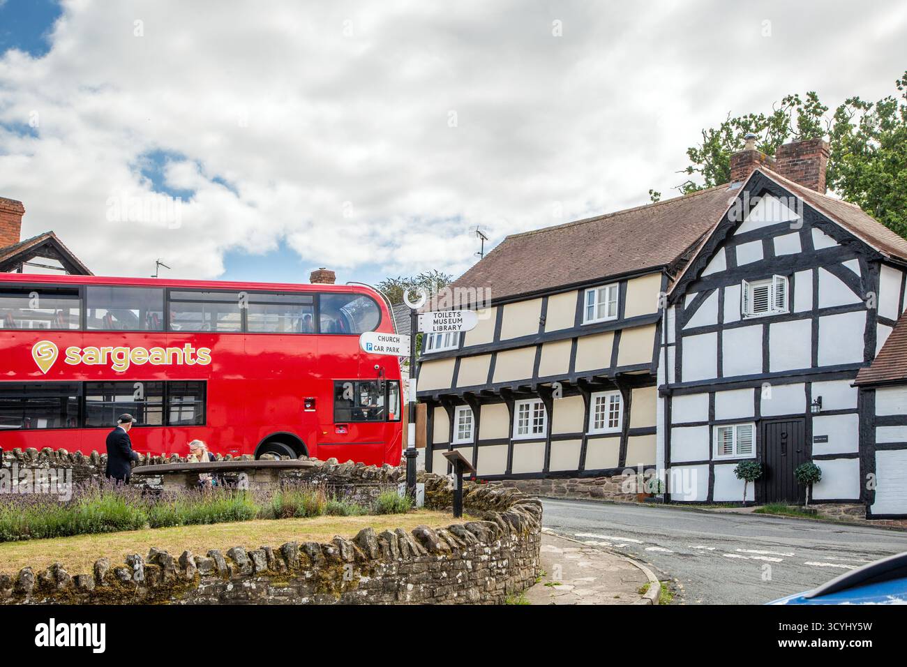 Bus à impériale et cottages de campagne à colombages noirs et blancs dans le village de Weobley dans le Herefordshire, partie de la piste noire et blanche. Banque D'Images