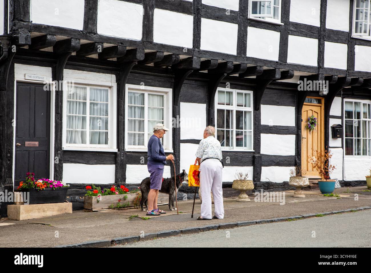 Deux personnes parlant à l'extérieur des cottages de campagne à colombages noirs et blancs dans le village de Weobley Herefordshire partie de la piste noire et blanche. Banque D'Images
