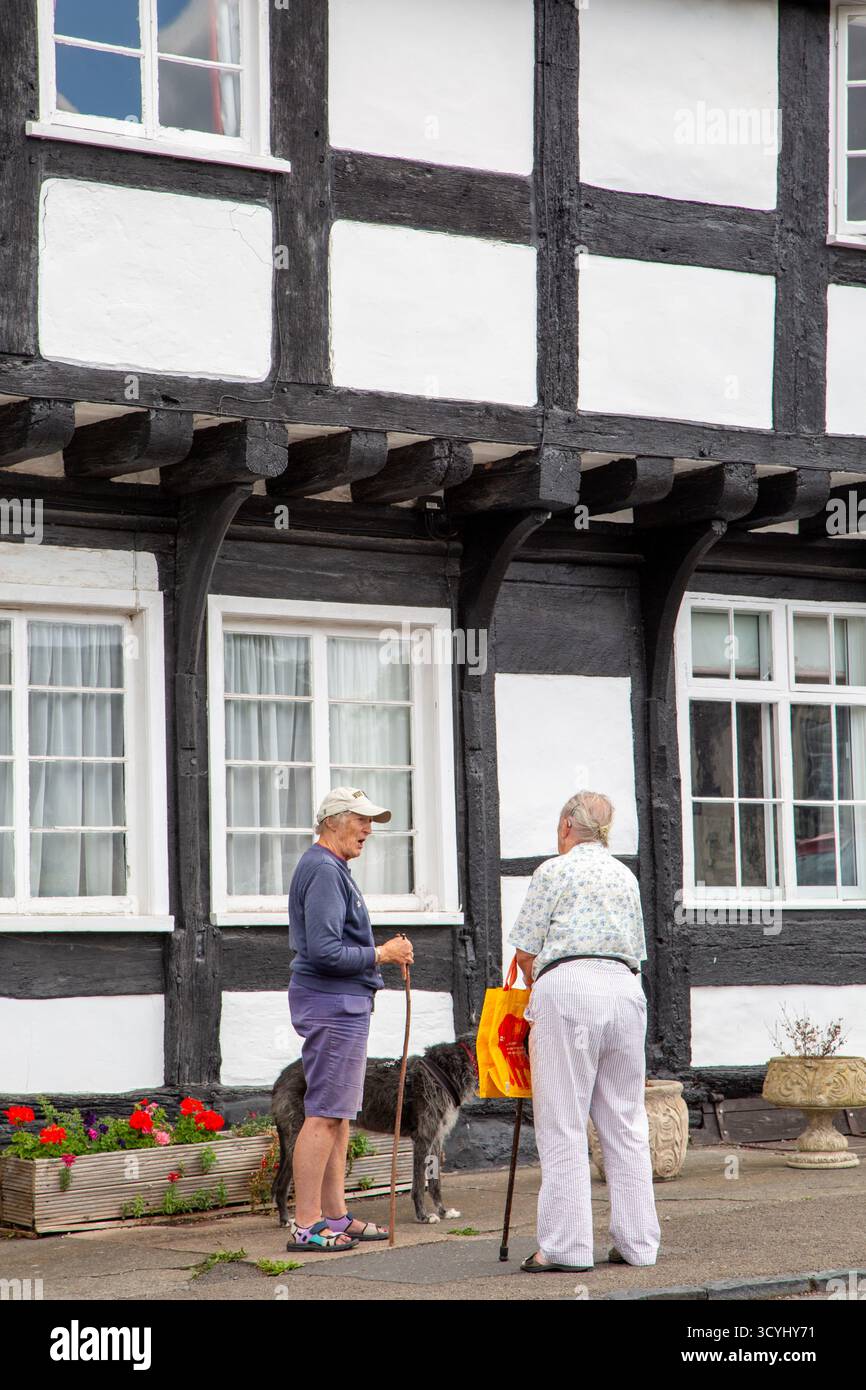 Deux personnes parlant à l'extérieur des cottages de campagne à colombages noirs et blancs dans le village de Weobley Herefordshire partie de la piste noire et blanche. Banque D'Images