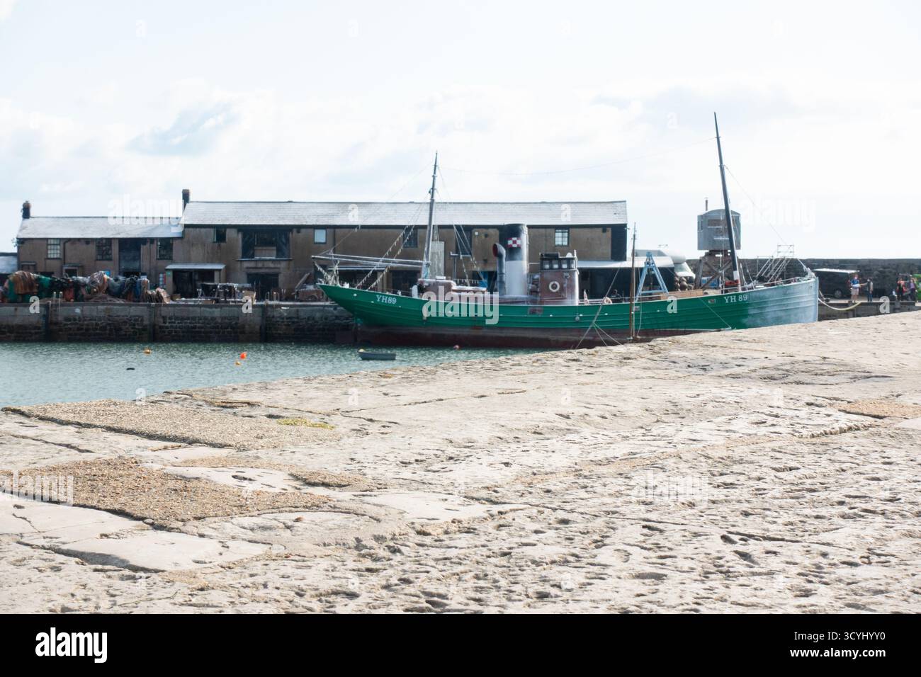 Bateau de pêche vert amarré à marée basse sur la plage de sable du port de Lyme Regis Banque D'Images