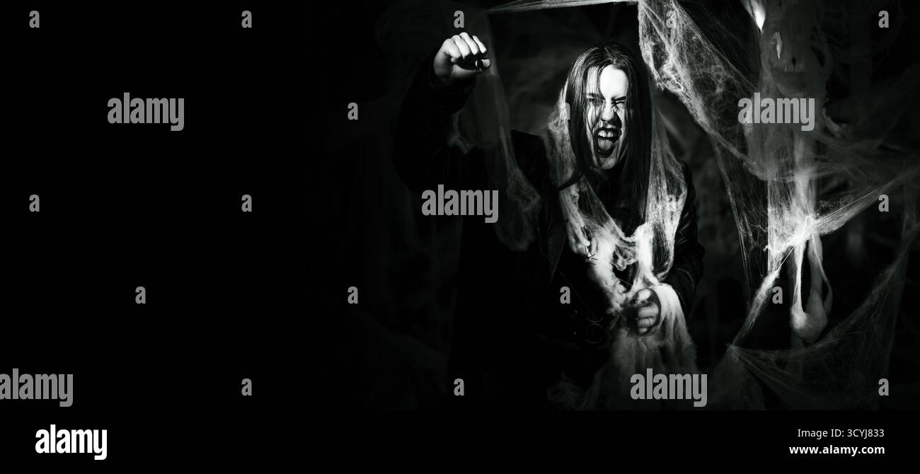 femme gothique avec le maquillage vampire effrayant piégé dans la toile d'araignée essayant d'effrayer montrant le geste de grève et poing-up. Fantaisie effrayante fille sur halloween retour Banque D'Images