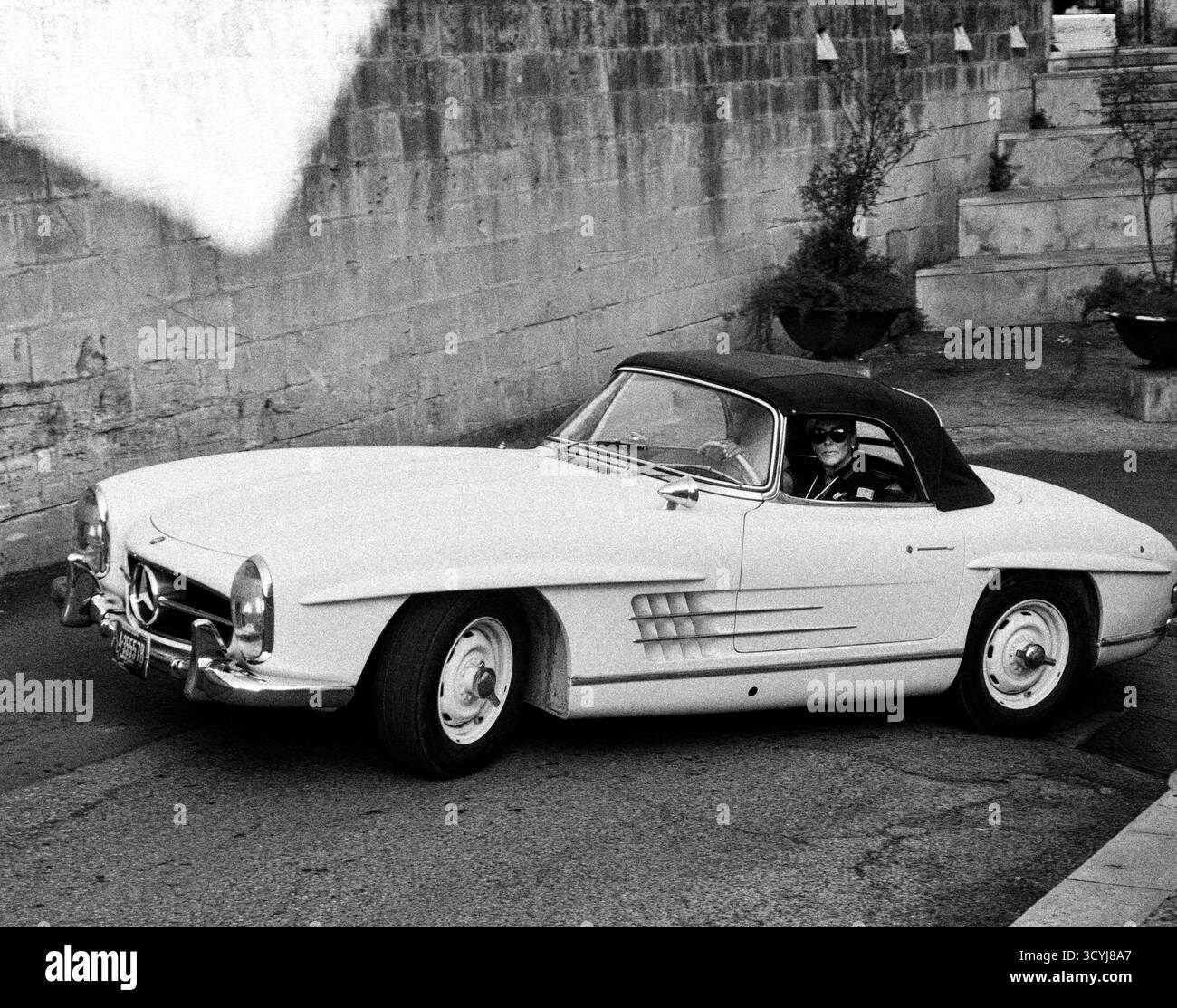 Voiture de sport classique conduite dans les rues du village italien en noir et blanc Banque D'Images