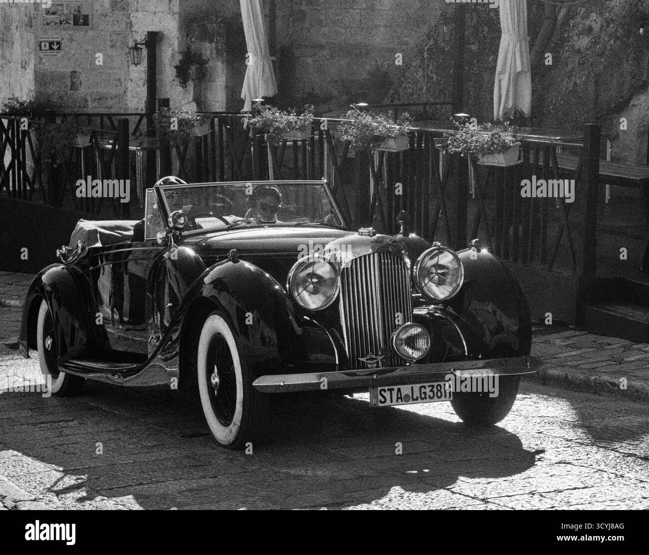 Voiture de sport classique conduite dans les rues du village italien en noir et blanc Banque D'Images