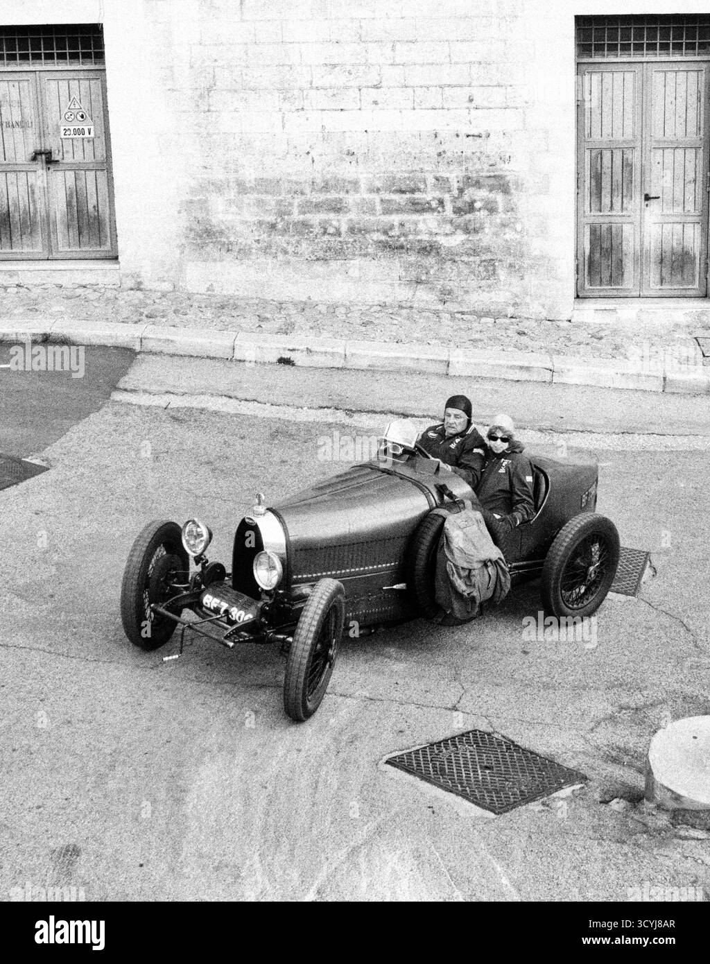 Voiture de sport classique conduite dans les rues du village italien en noir et blanc Banque D'Images