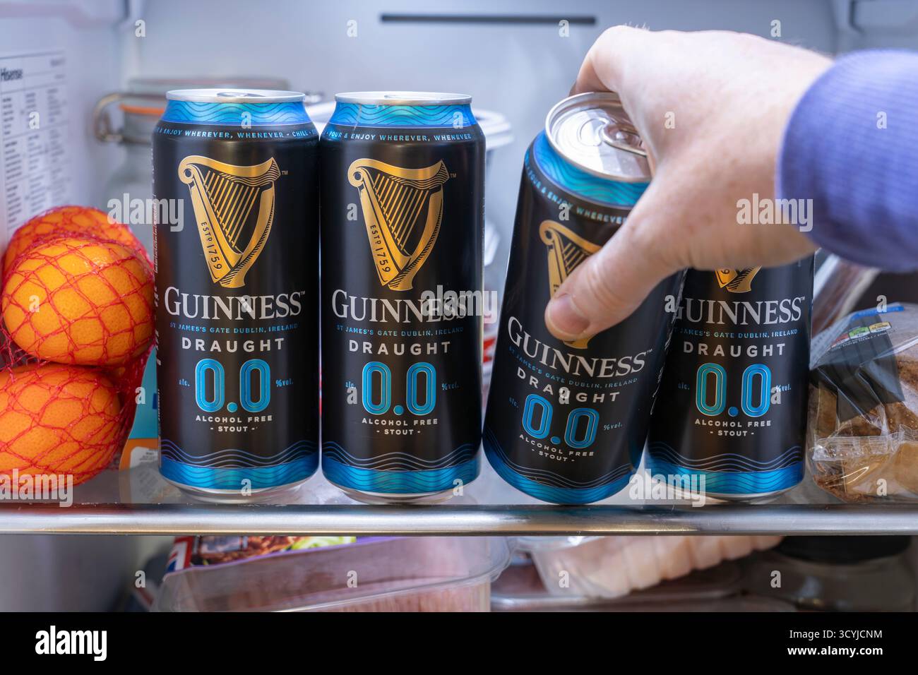 Homme d'âge moyen sélectionnant une canette de bière robuste sans alcool Guinness ZERO 0,0 dans un réfrigérateur, Angleterre. Les gens sont maintenant plus soucieux de leur santé et boivent moins Banque D'Images