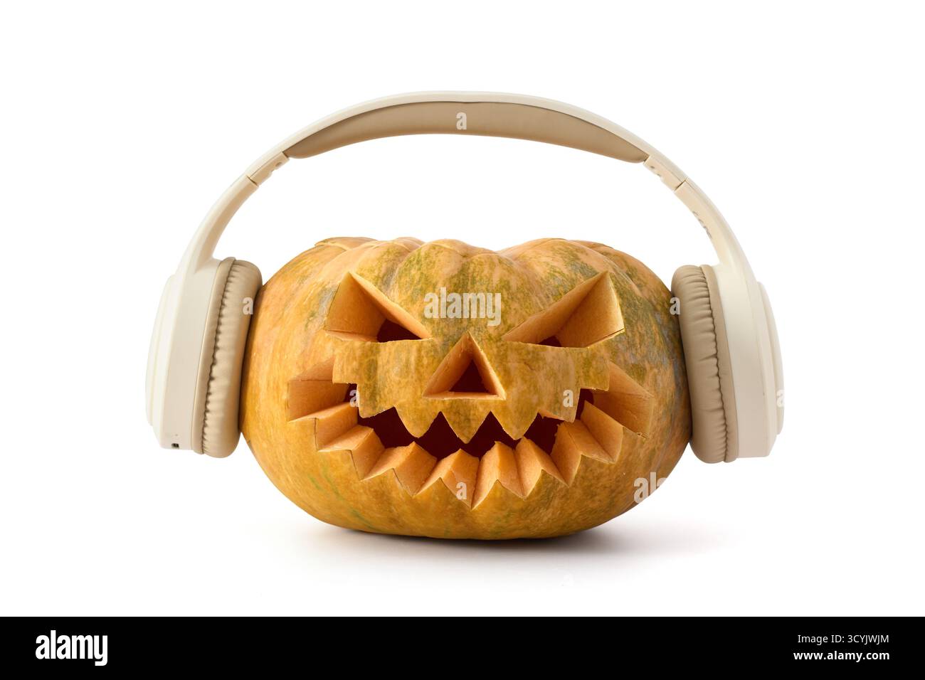 Citrouille d'Halloween drôle avec le visage sculpté portant des écouteurs sur un fond blanc Banque D'Images