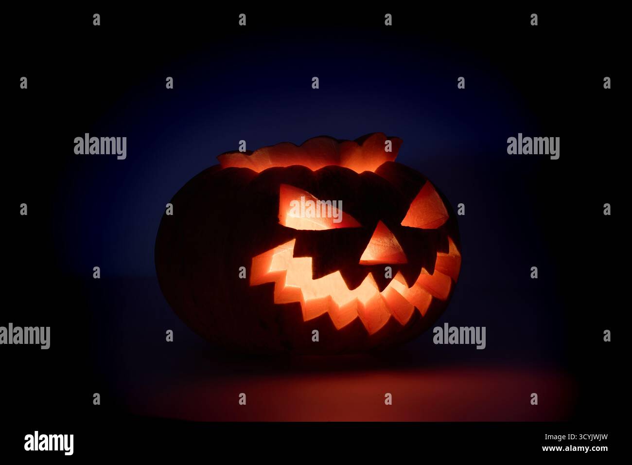 Une citrouille sculptée avec un visage de jack-o'-lanterne incandescent est illuminée sur un fond sombre Banque D'Images
