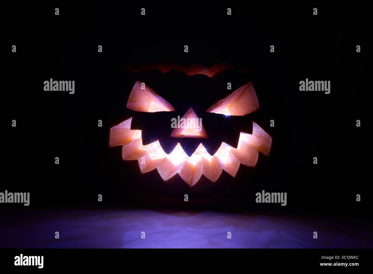 Une citrouille sculptée avec un visage de jack-o'-lanterne incandescent est illuminée sur un fond sombre Banque D'Images