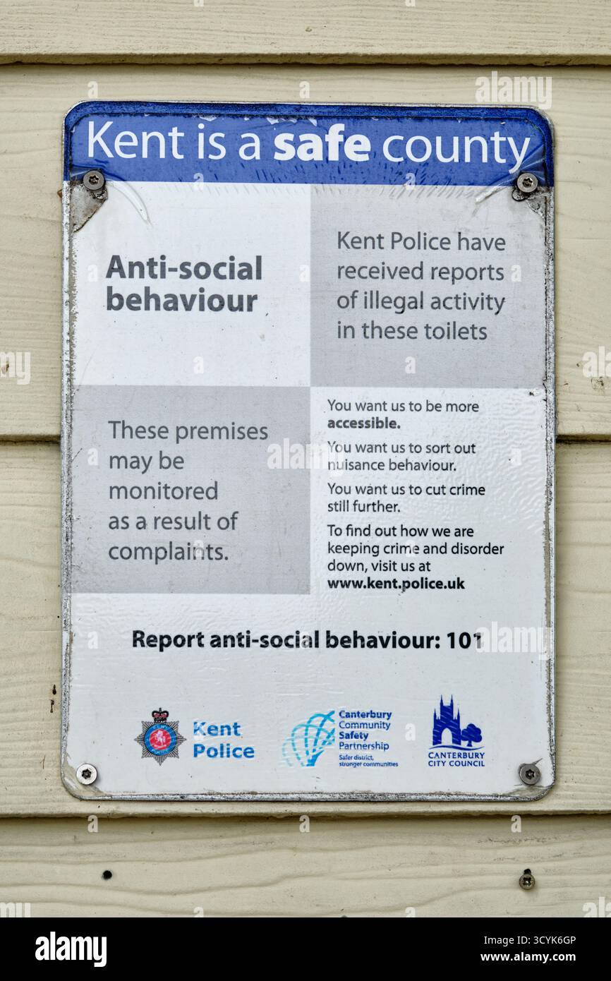Panneau d'avertissement de comportement antisocial et de surveillance policière sur le mur des toilettes publiques à Westgate Gardens, Canterbury, Kent, Royaume-Uni Banque D'Images